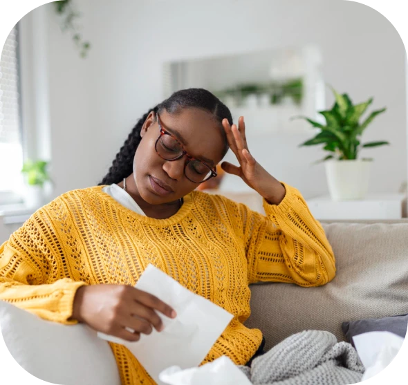 Woman in a yellow sweater looking stressed while reviewing financial documents